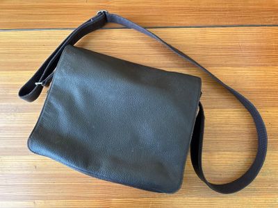 a black leather purse sitting on top of a wooden floor