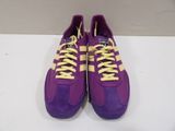 purple and yellow sneakers with yellow laces on them on a white surface