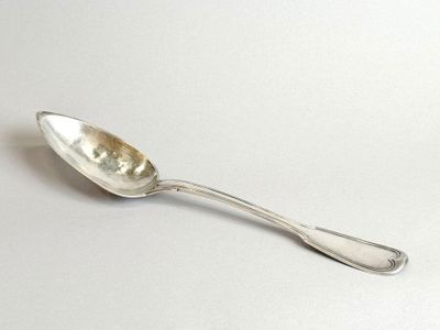 silver spoon sitting on a white surface with a silver handle