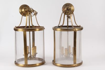 pair of brass and glass lanterns with candles on each of them