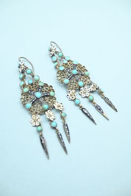 a pair of earrings with turquoise beads and silver spikes on them