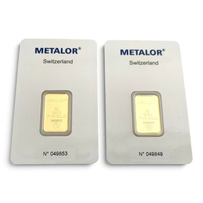 Deux lingots d'or sont posés côte à côte sur une surface blanche.