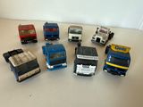 Plusieurs camions miniatures sont alignés sur une surface blanche