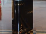 a black lighter sitting on a wooden table next to a book