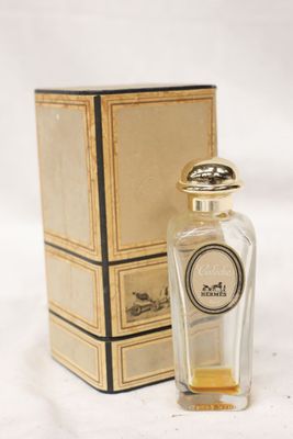 un vieux flacon de parfum posé à côté d'une boîte sur une surface blanche