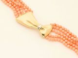 a close up of a necklace on a white surface with a gold clasp