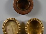 Deux objets plaqués or, l'un orné de l'effigie d'une femme et l'autre de celle d'un homme, sont posés sur une surface blanche
