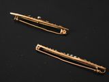 two gold bobby pins sitting on a black surface