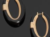 deux paires de boucles d'oreilles créoles noires et dorées posées sur un fond noir