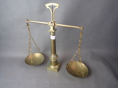 une balance ancienne en laiton comportant deux plateaux de chaque côté