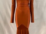 une robe orange posée sur un mannequin, devant un fond blanc