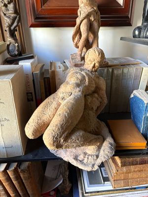 a statue of a man sitting on top of a pile of books