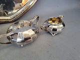 two silver teapots on a table next to a mirror