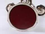 a close up of a red button on a silver cuff