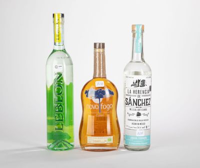 trois bouteilles d'alcool sont alignées sur une surface blanche