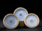 quatre assiettes bleues et blanches à bord doré, posées sur un fond noir