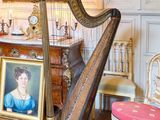 une grande harpe au milieu d'une pièce où est accroché un tableau au mur