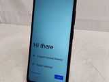 the back of a black phone with a blue screen on a white surface