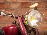 a close up of a red motorcycle with a brick wall in the background