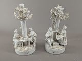 une paire de figurines en porcelaine blanche représentant un homme et une femme assis sous un arbre
