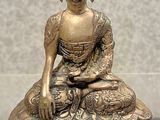 brass statue of a seated buddha on a table with a price tag in front of it