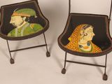 pair of hand painted chairs on wheels with a man and a woman on them
