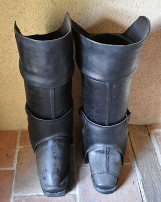 paire de bottes en cuir noir posées sur un sol carrelé