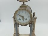 une horloge posée sur un support sur une surface blanche