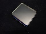 a small square metal object on a black surface