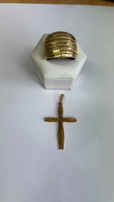 une croix et une bague en or posées sur une table blanche