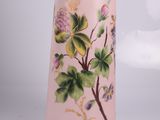 a pink vase with flowers painted on it sitting on a table