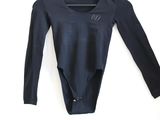 a black bodysuit hanging on a hanger on a white wall