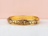 a close up of a gold bracelet on a white surface