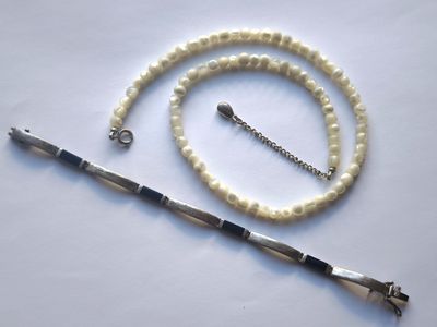 un collier blanc avec un fermoir en argent et un collier de perles blanches