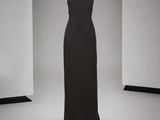 une robe noire sur un mannequin posé sur un socle, dans une pièce