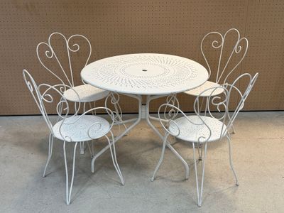 une table blanche et quatre chaises devant un mur marron