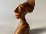 une image représentant une sculpture en bois d'une femme portant un chapeau sur la tête