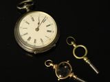 une montre de poche et une clé posées sur une surface noire