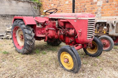 un tracteur rouge garé devant un bâtiment en briques