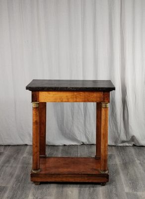 une table en bois avec un plateau en marbre noir, posée sur un parquet