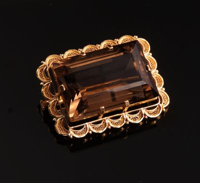 un gros plan d'une broche en or sertie d'une pierre marron