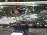 a man taking a picture of himself in the reflection of a car window