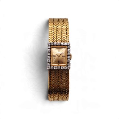 un gros plan d'une montre en or sertie de diamants sur fond blanc