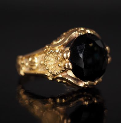 a gold ring with a black stone on a black surface