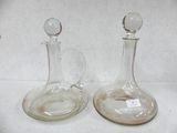 two glass decanters sitting on a white surface