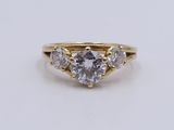 a yellow gold engagement ring with three round diamonds