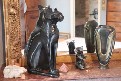 a statue of a cat sitting on top of a table next to a mirror