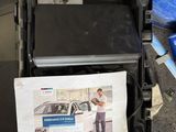 une photo d'un homme debout à côté d'un carton sur lequel figure l'image d'une voiture