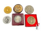 quatre types de pièces différents dans une boîte rouge posée sur une surface blanche