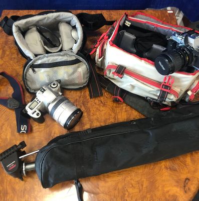 une table sur laquelle se trouvent un appareil photo, un étui pour appareil photo, un appareil photo et d'autres objets
